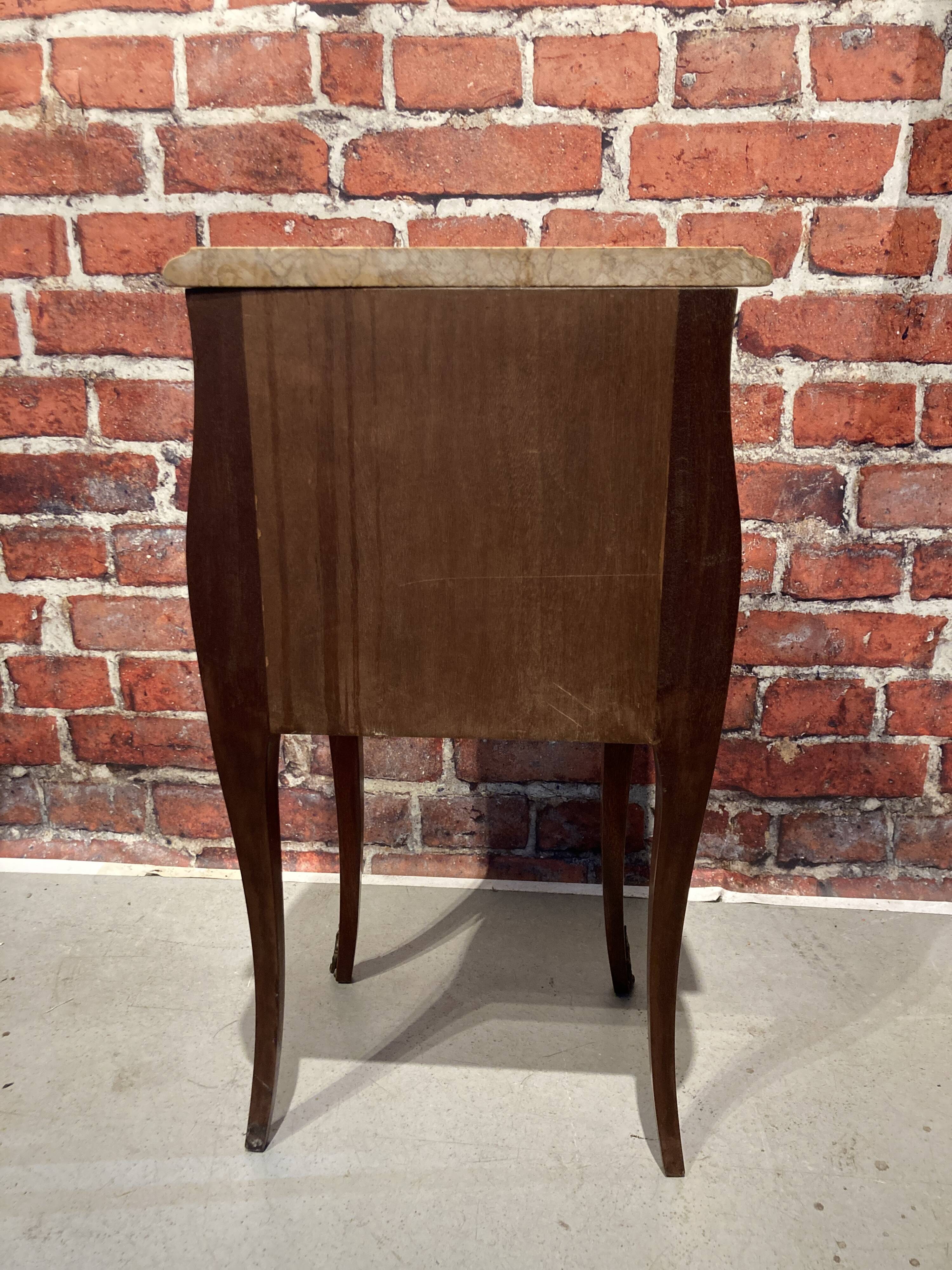 Wooden bedside table topped with a pink marble top