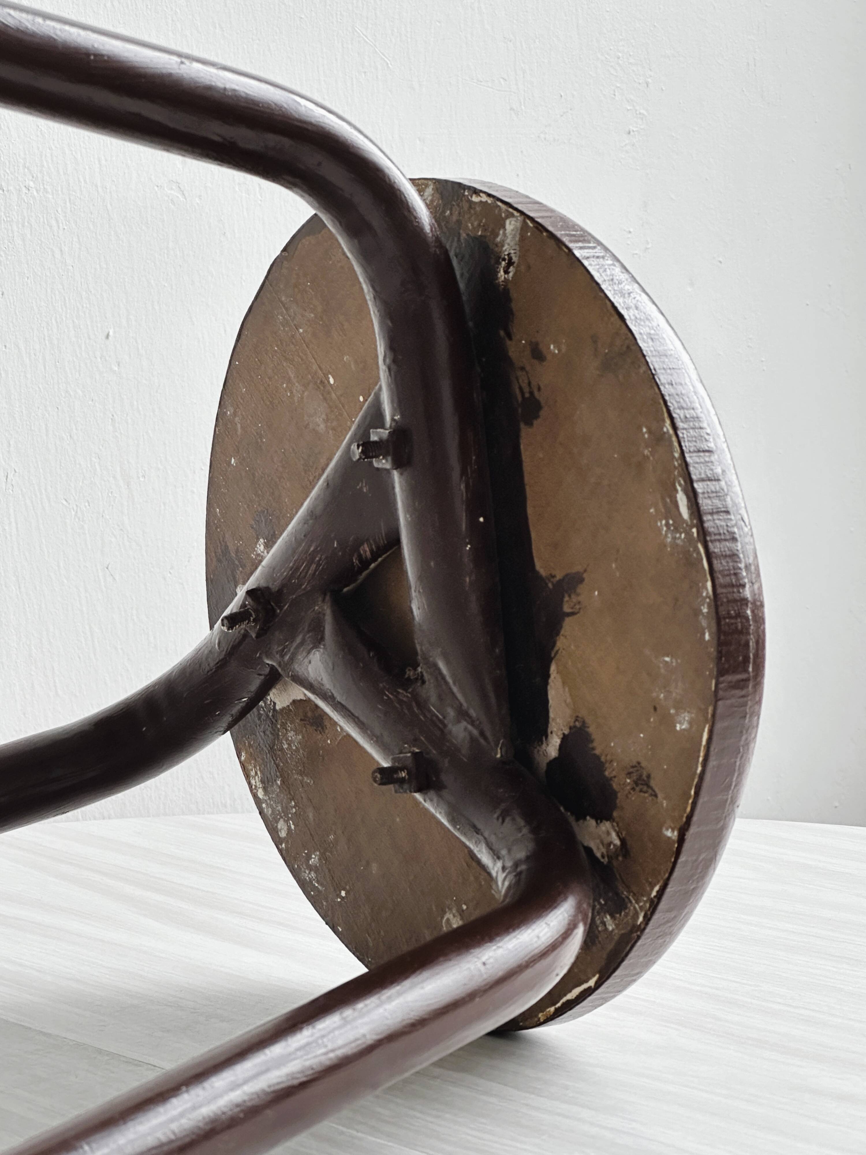 Dark brown metal stool, minimalist three-legged design