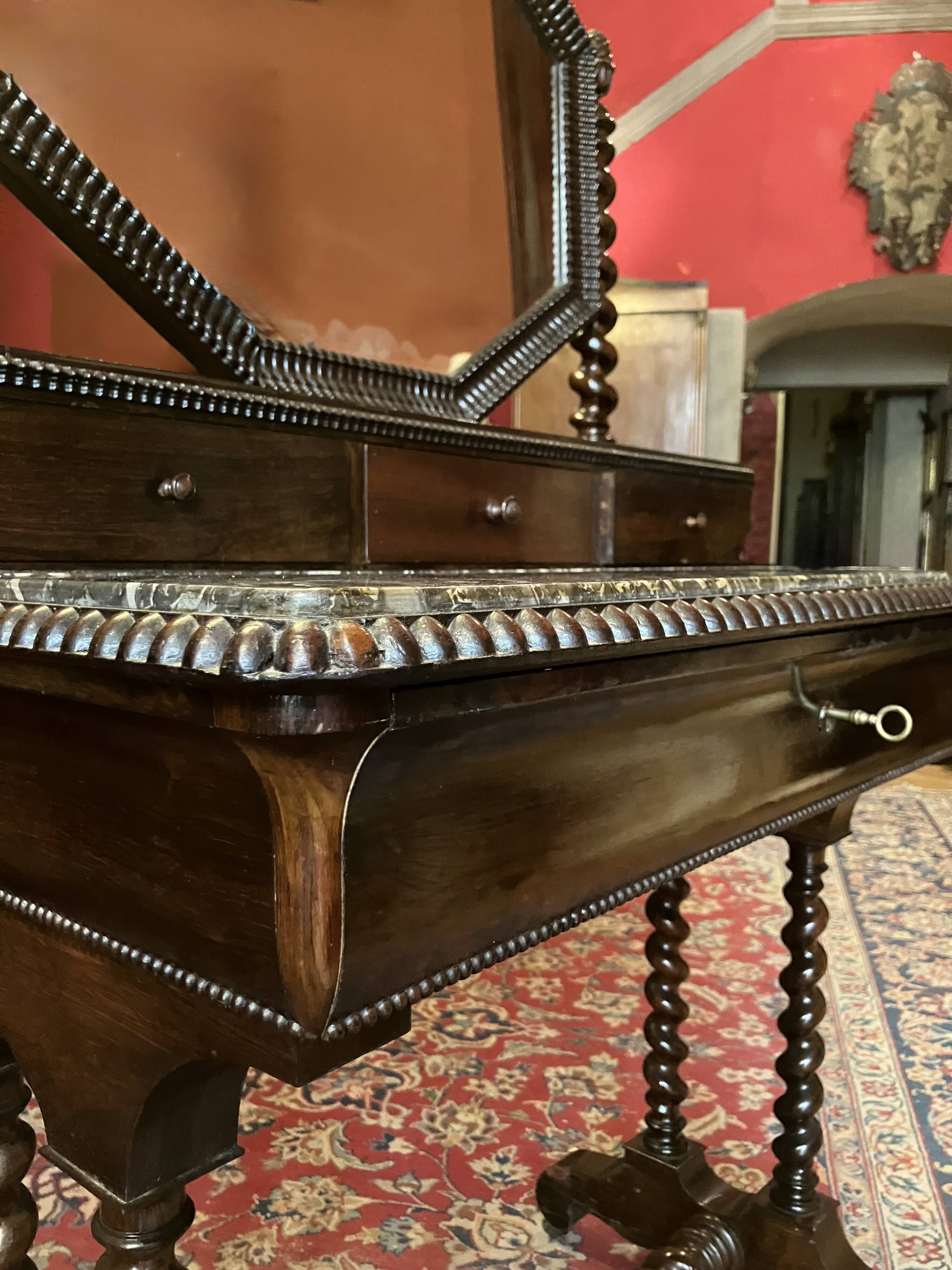 Antique English mahogany dressing table with carved details, black marble, and mirror.