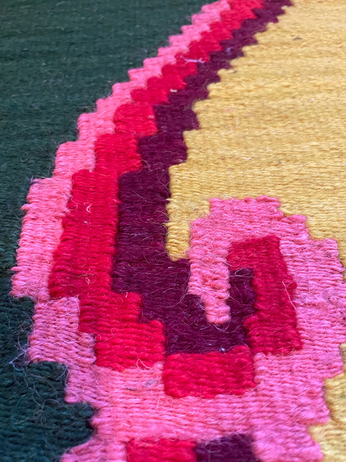 Vintage wool rug with pink flowers on green and yellow background made by hand in Transylvania