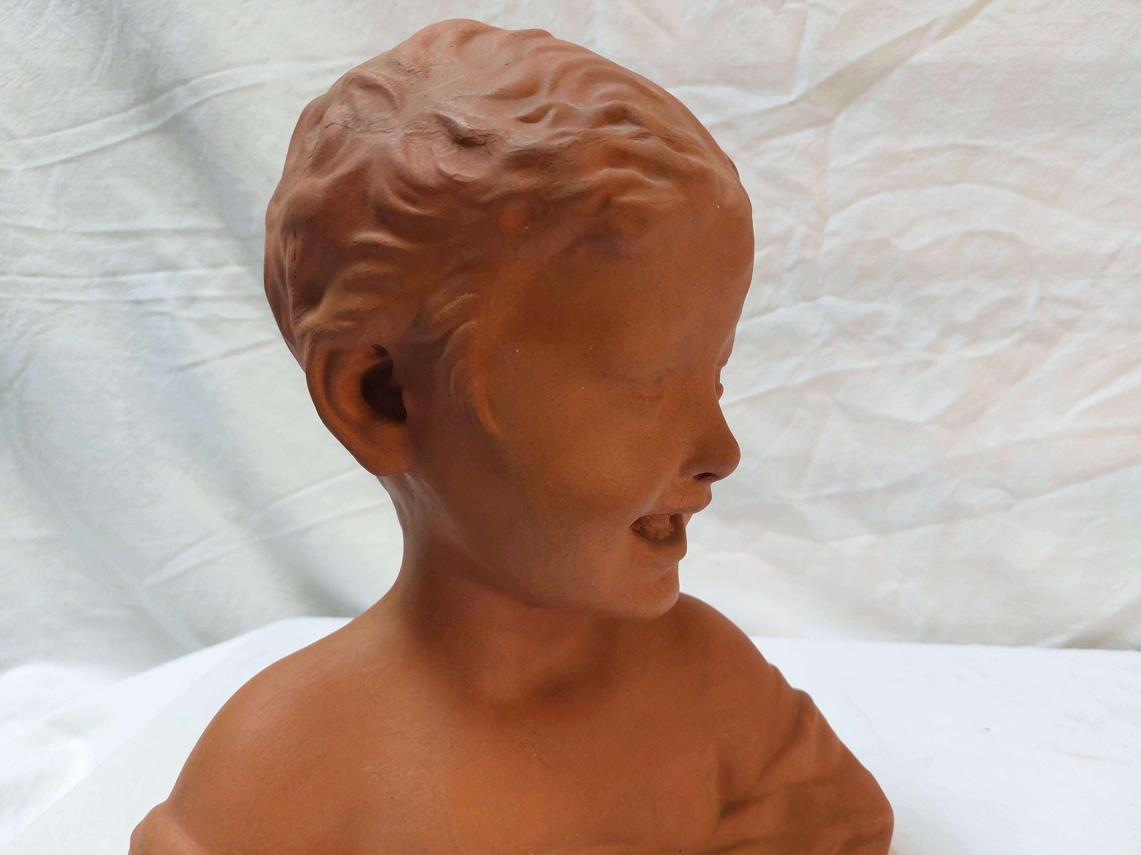 Terracotta bust of a smiling little boy.