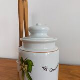 Vintage porcelain pickle pot with wooden pliers.