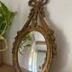 Oval convex witch mirror with golden ribbon mouldings.