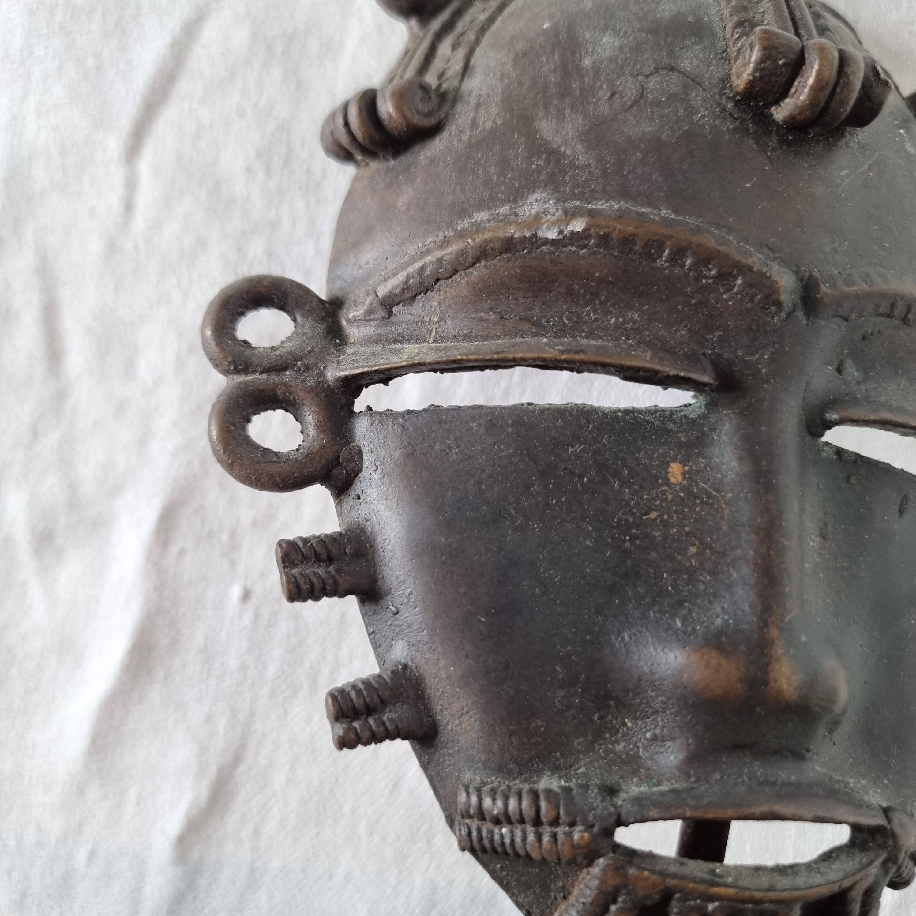 African bronze mask on pedestal, from Ivory Coast, dating
