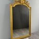 Large antique gilded wooden mirror in Louis XVI style with a sculpted pediment, 19th century.