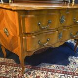 Large bow-fronted chest of drawers in blonde cherry with bronze ornamentation.