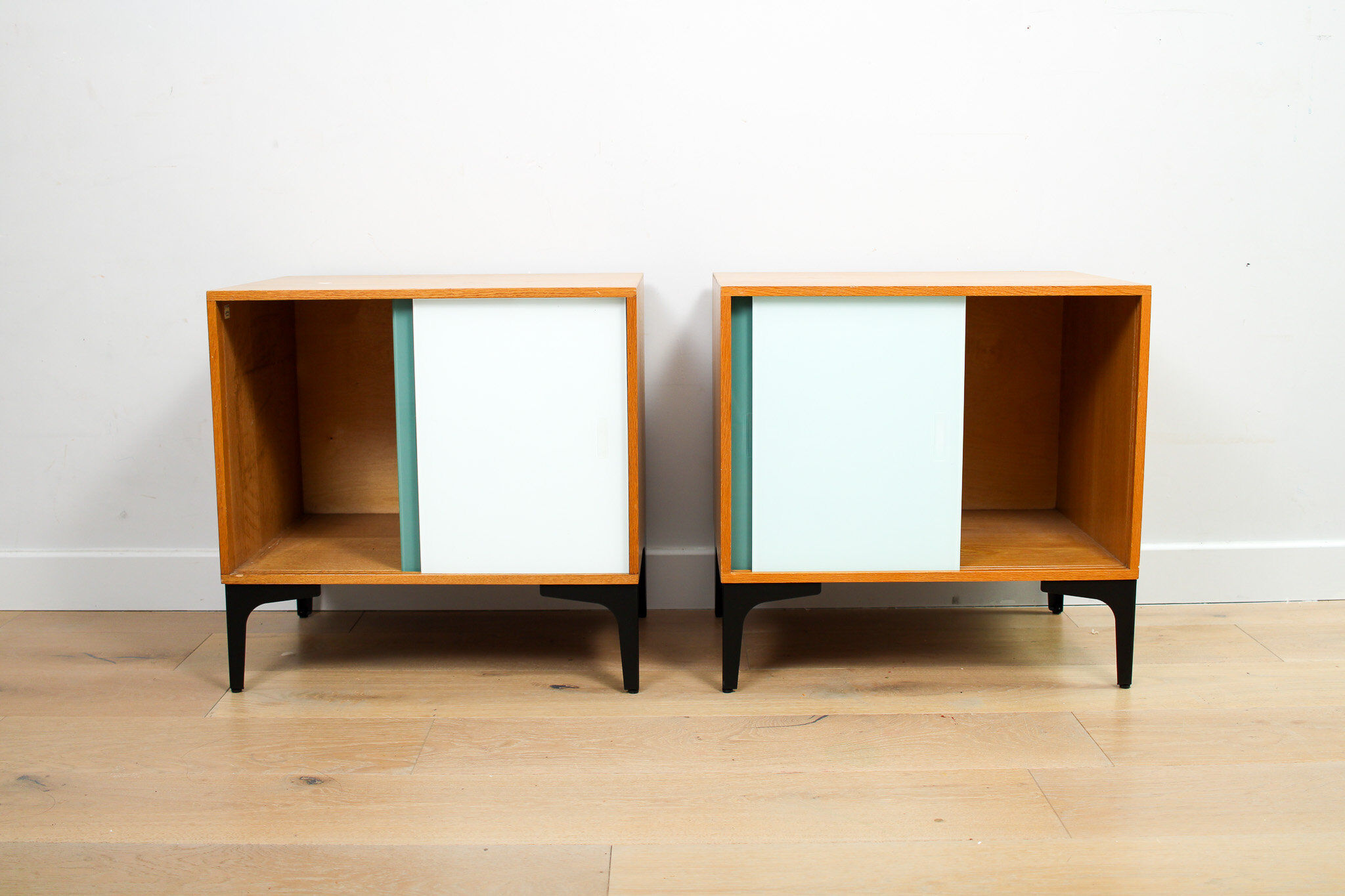 A pair of vintage mid-century bedside tables with glass sliding doors