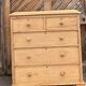 Large antique English chest of drawers in raw solid wood.