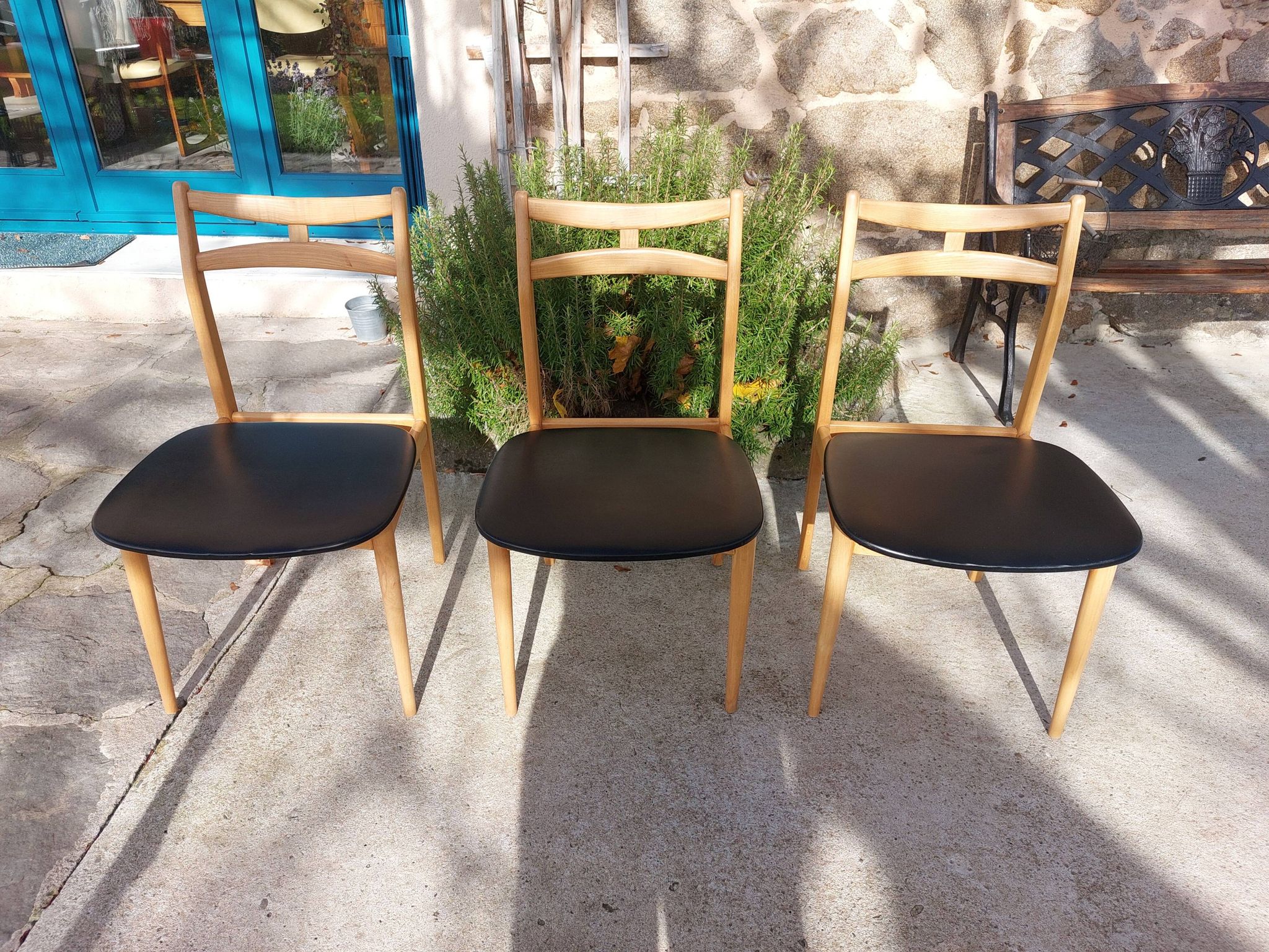 3 Scandinavian style chairs, light wood and black faux leather.