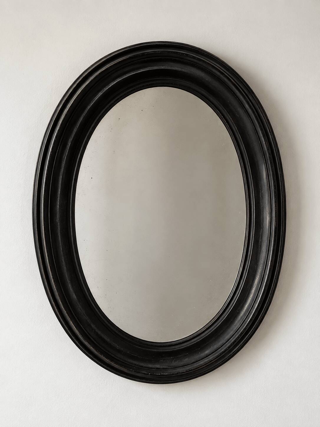 Antique oval mirror in patinated black wood