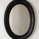 Antique oval mirror in patinated black wood