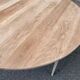 Large extendable round dining table stripped in solid cherry wood with a central leg.