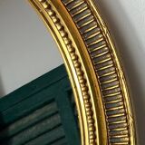 Oval-shaped wooden mirror in gold color