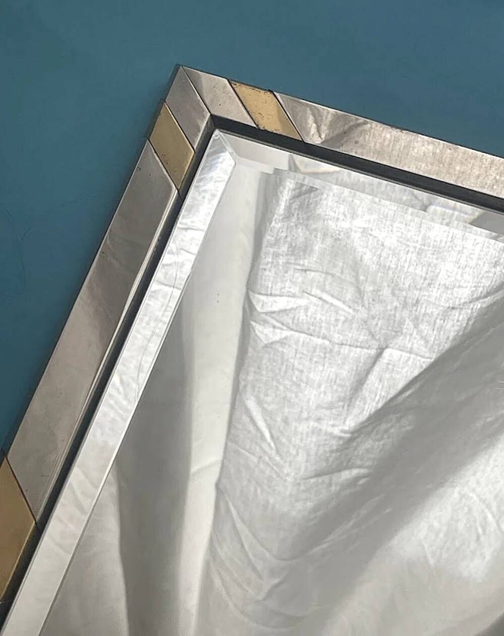 Faceted modernist wall mirror in steel and brass, geometric mixed metal frame 1970s.