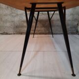 Table à manger en bois de teck et pieds en métal peint.
