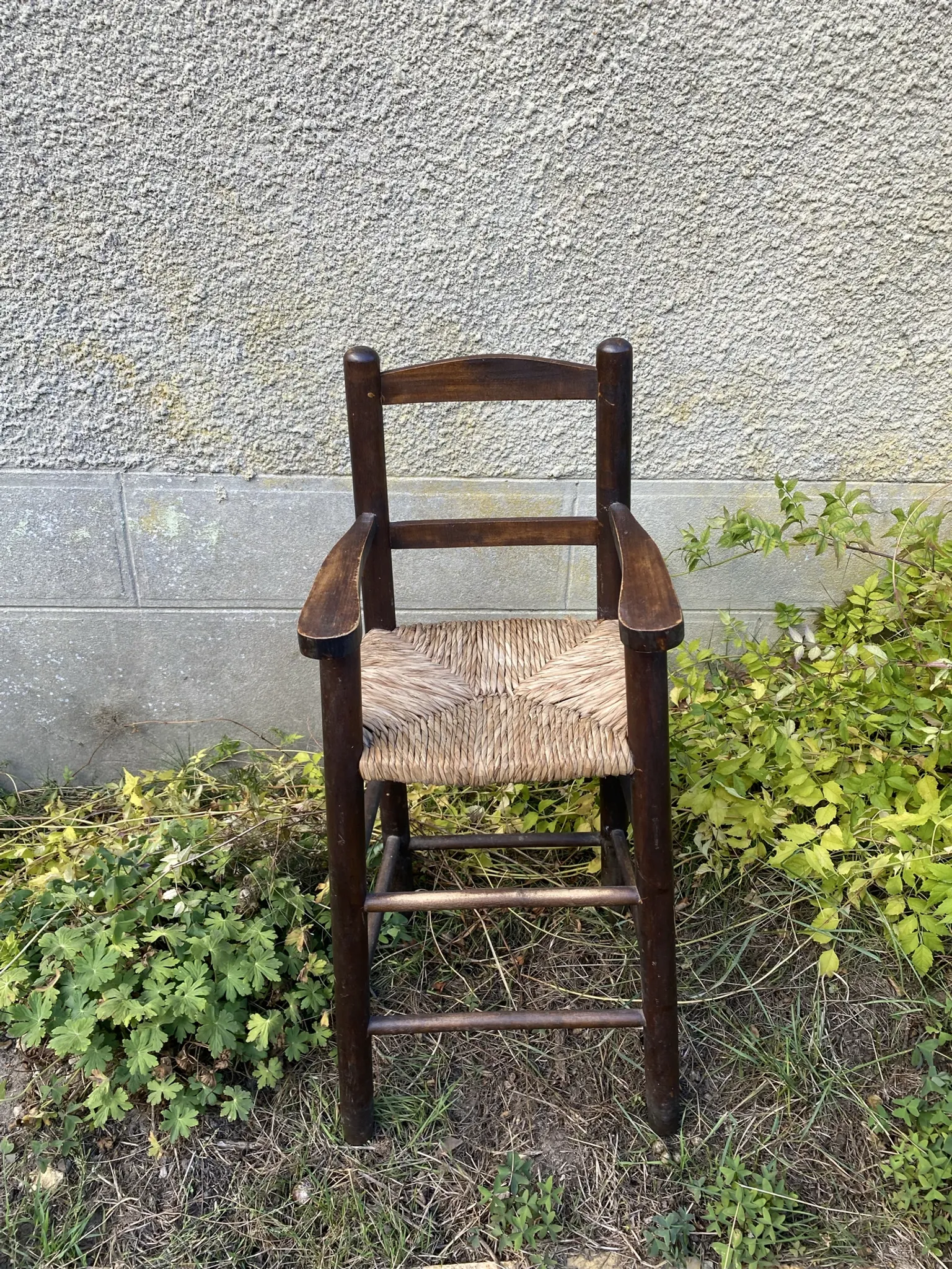 Vintage wooden children's high chair with straw.