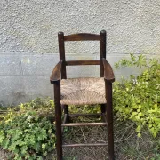 Vintage wooden children's high chair with straw.