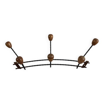 Wall-mounted coat rack in wrought iron with turned wooden knobs.