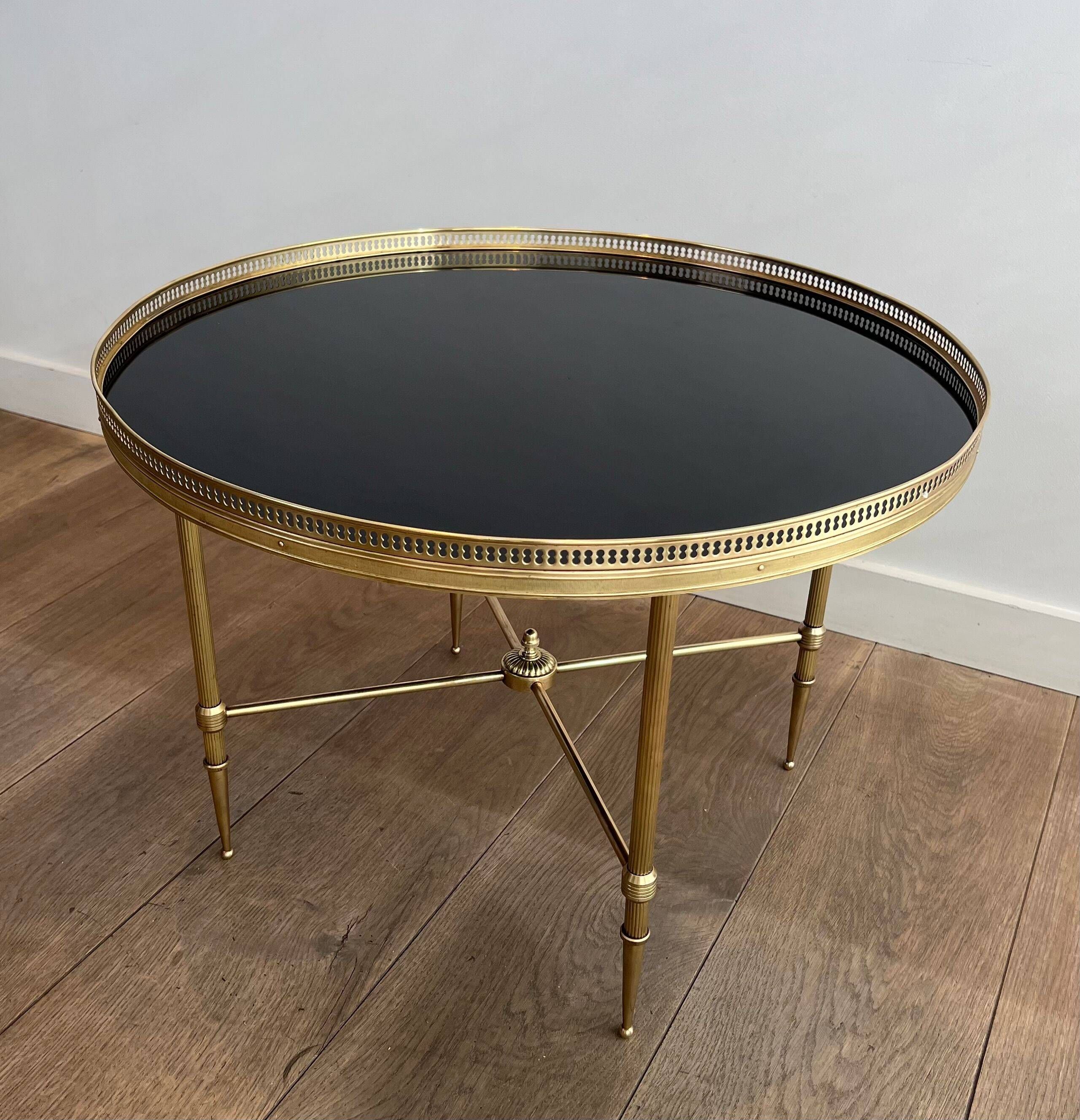 Round coffee table in brass with a black lacquered glass top from Maison Jansen.