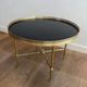 Round coffee table in brass with a black lacquered glass top from Maison Jansen.