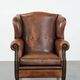 Sheepskin wingback armchair with decorative nails and black piping