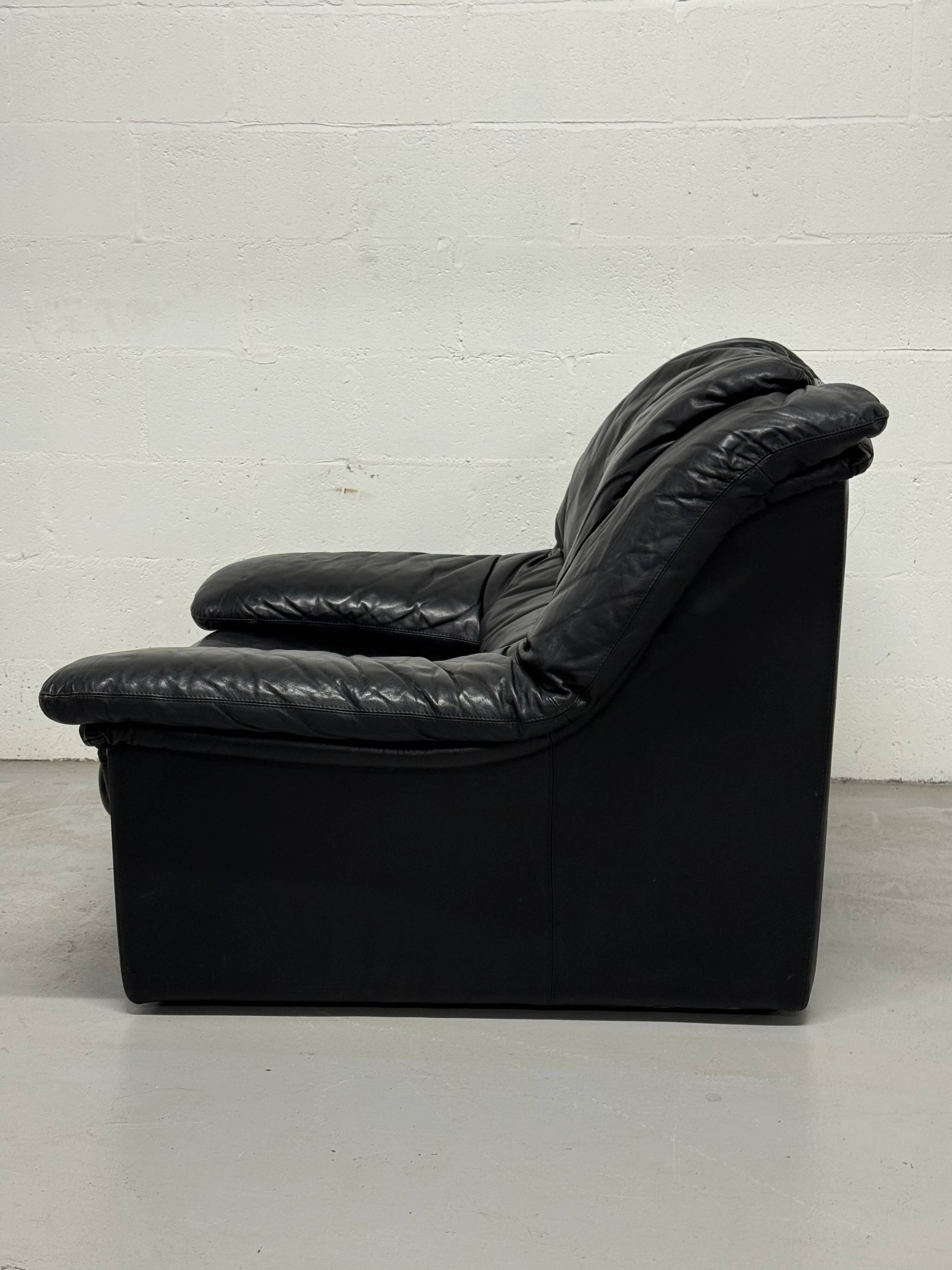 Vintage black leather lounge chair — low postmodern club chair from the space age.