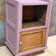 Pink bedside table with haberdashery and raw wood.