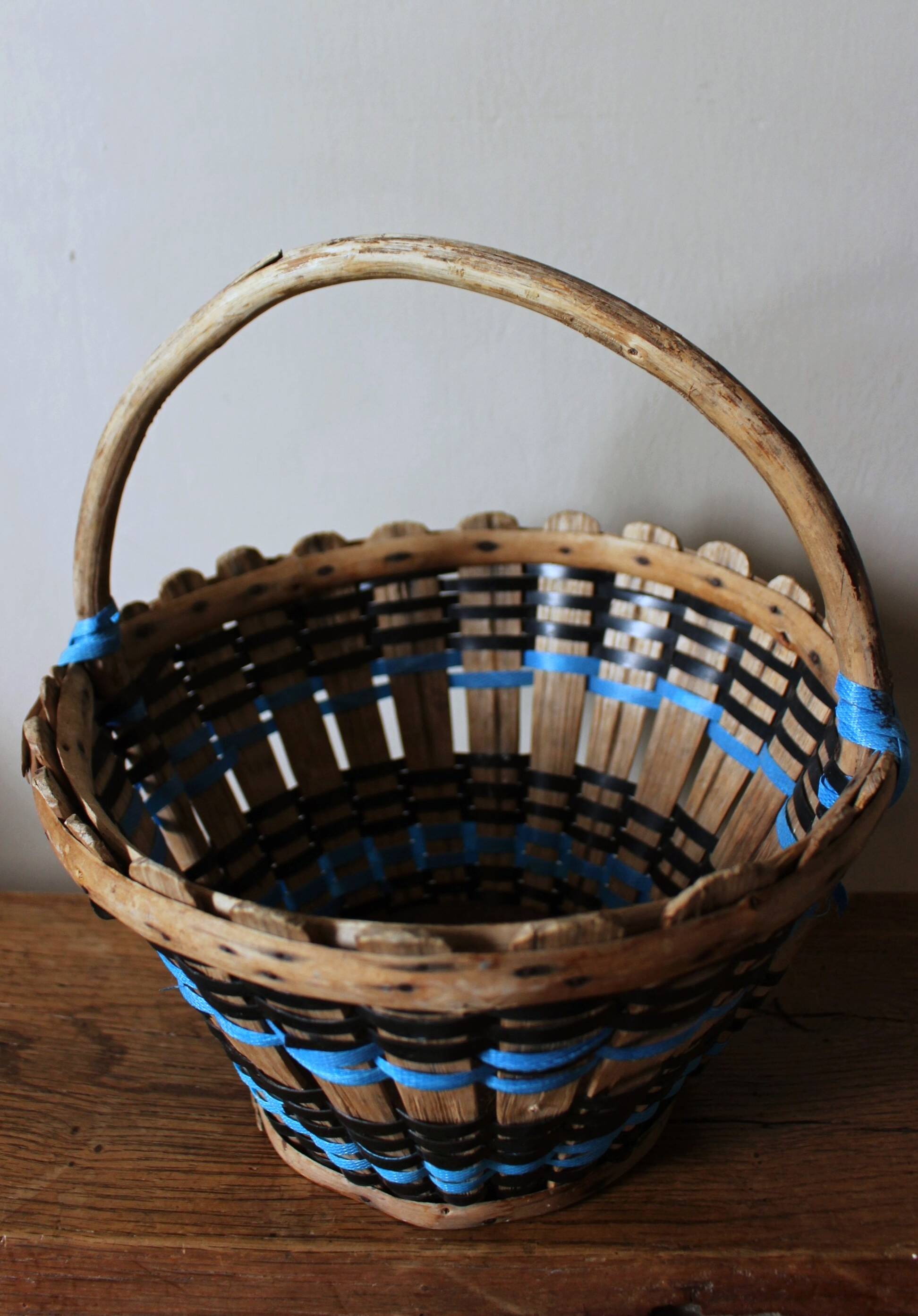 Vintage wooden basket with round handle, blue and black weaving.