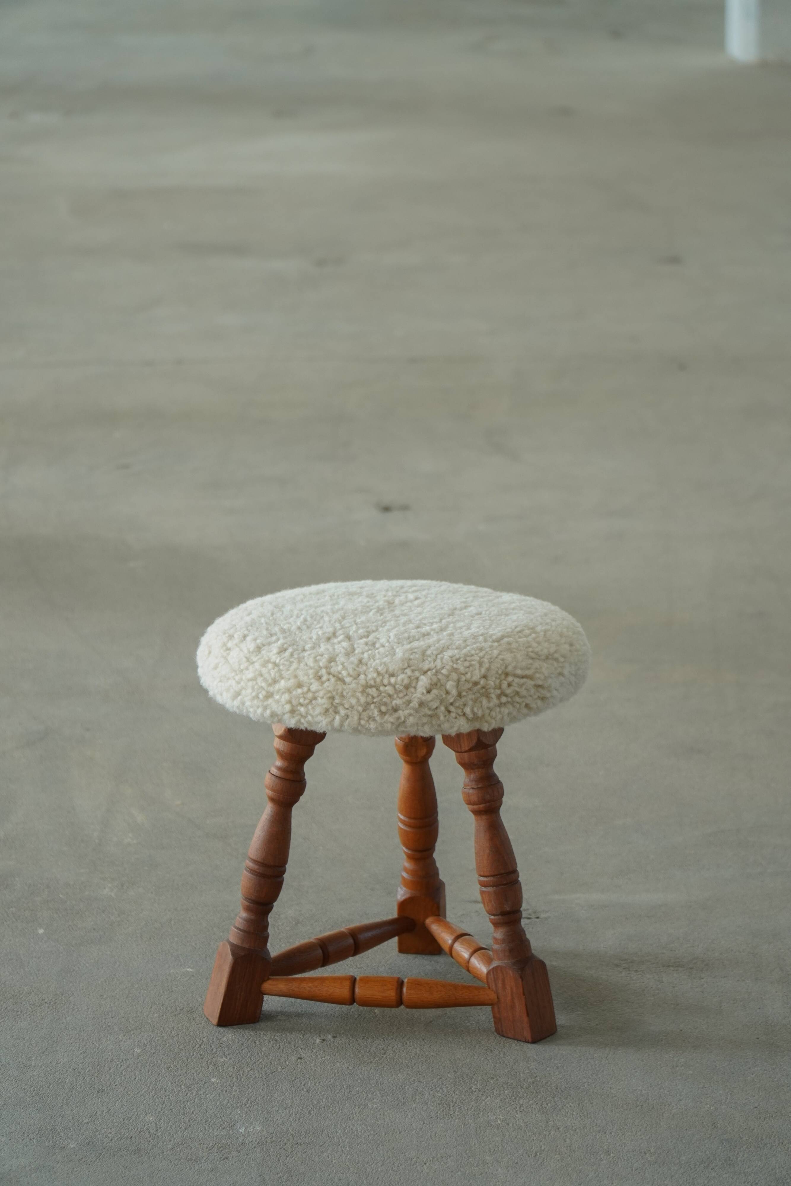 Modern Danish stool, with three oak legs featuring turned feet and a lambswool seat, 1950s.
