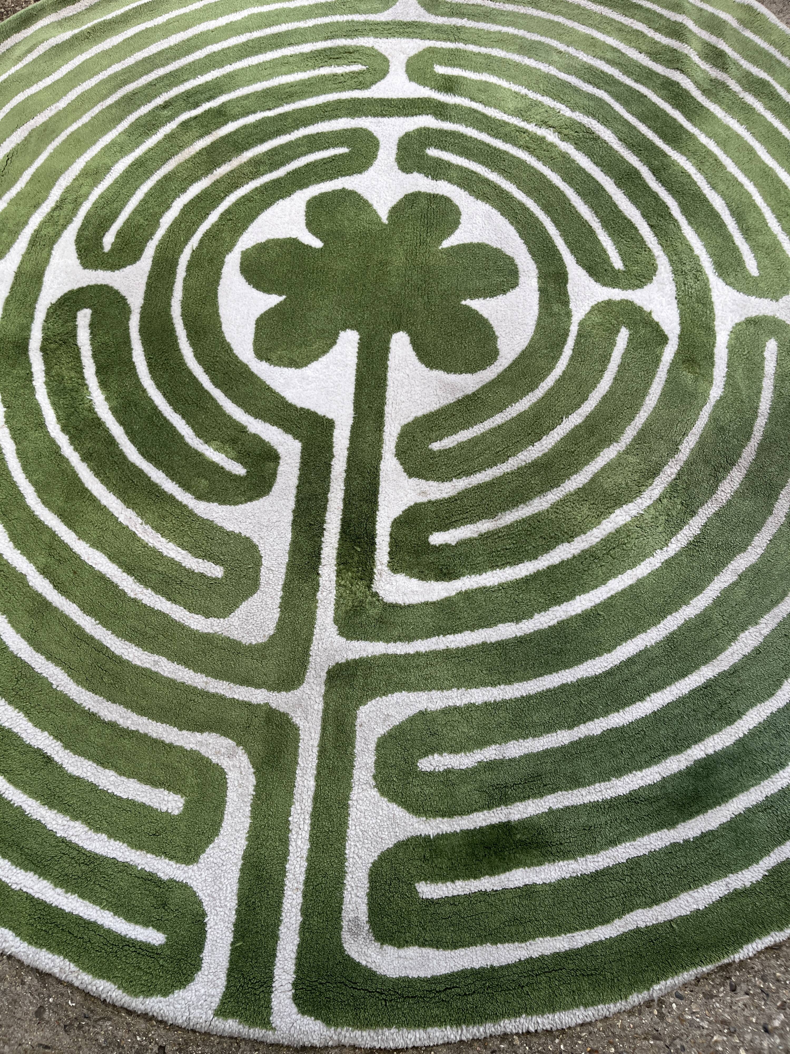 Circular rug with green decor on a cream background from the Labyrinth.