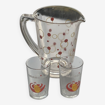 Carafe with polka dots and bubbles, red and yellow and 2 orangina advertising glasses, lemonade glass