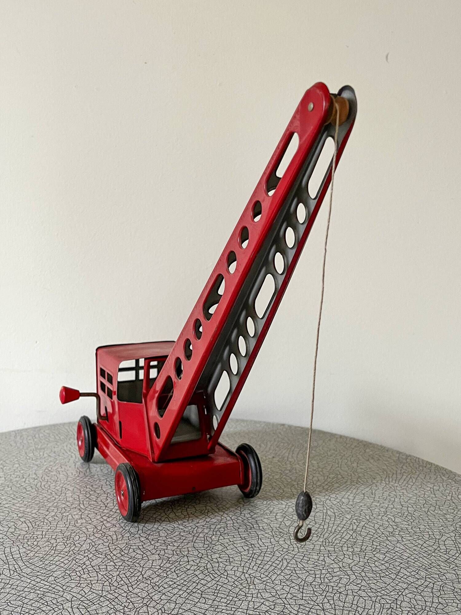 Grue de chantier rouge en tôle datant des années 60 avec mécanisme manuel