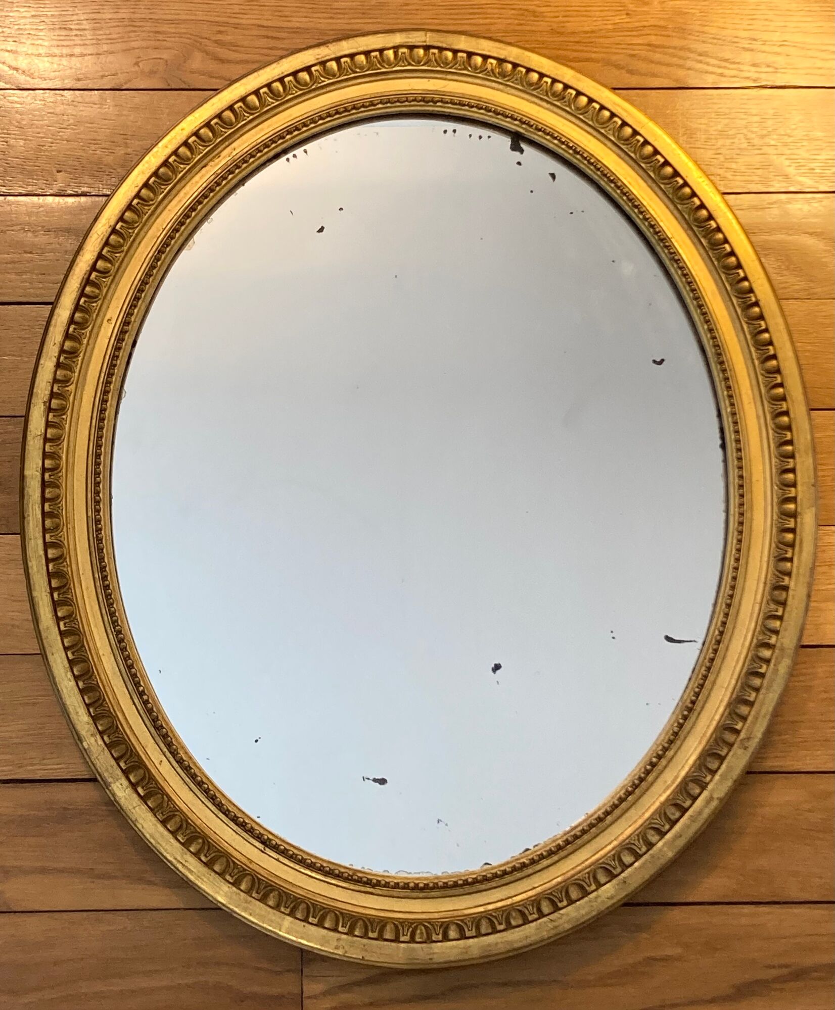 Oval mirror in carved wood, stuccoed and gilded with leaf Louis XVI style late nineteenth century