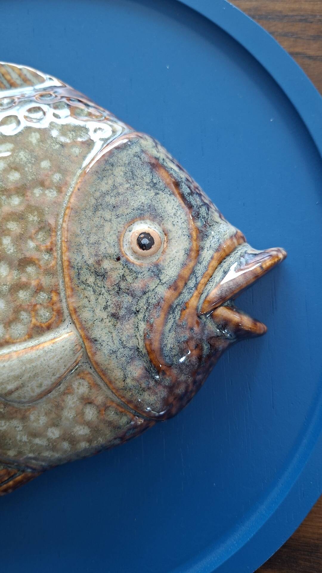 Vallauris ceramic wall sculpture of a relief fish on a blue plaque.