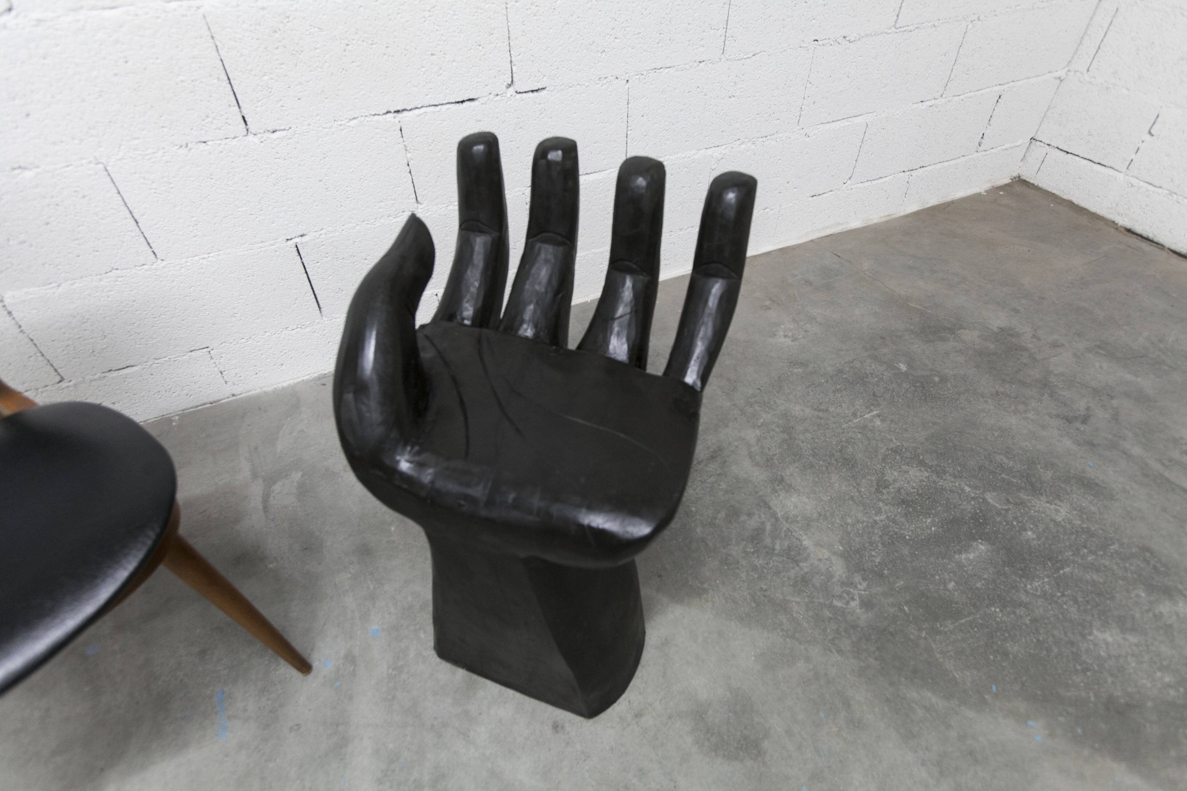 Black armchair chair in carved wood in the shape of a hand