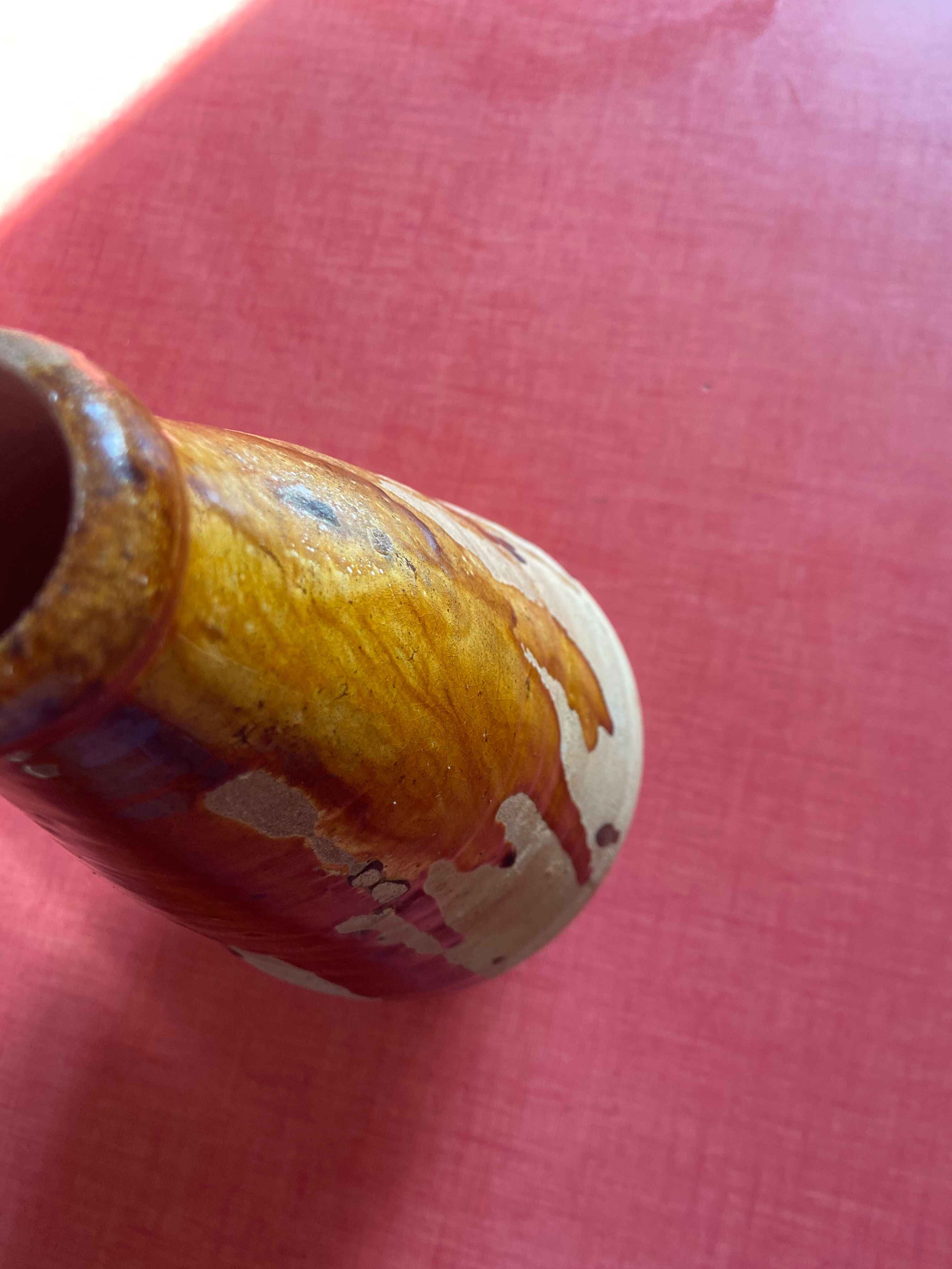 Large antique pottery bottle in glazed terracotta with drips.