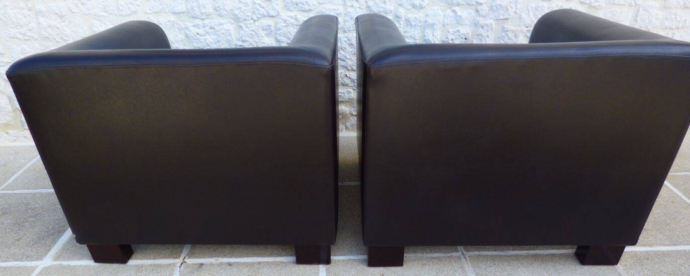 2 club armchairs with a chocolate faux leather seat and backrest and wooden legs.