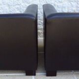 2 club armchairs with a chocolate faux leather seat and backrest and wooden legs.