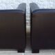 2 club armchairs with a chocolate faux leather seat and backrest and wooden legs.