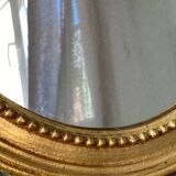 Oval-shaped wooden mirror in gold color