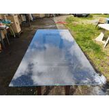 Vintage table with a glass top and smoked plastic trestle legs.