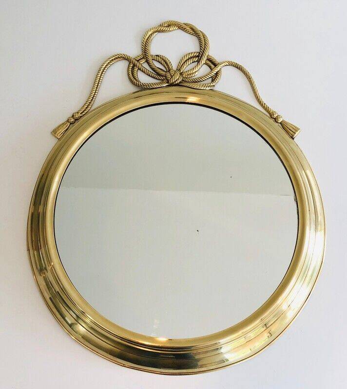 Large decorative oval mirror in brass adorned with a significant twisted bow.