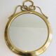 Large decorative oval mirror in brass adorned with a significant twisted bow.