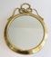 Large decorative oval mirror in brass adorned with a significant twisted bow.