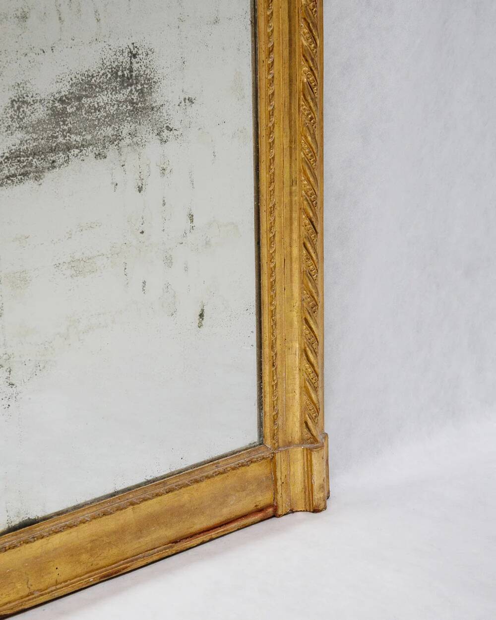19th-century patinated mirror with a ribbon-style frame