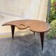 Mid-century coffee table with a palette shape and splayed legs.