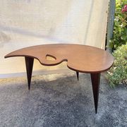 Mid-century coffee table with a palette shape and splayed legs.