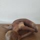 Wooden sculpted statuette of a woman in a pensive pose.