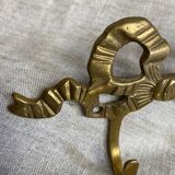 Two-hook coat rack with knot and ribbon in brass