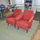Pair of Mid-Century armchairs in red and brown fabric with dark wooden legs.